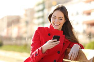 Girl sat on park bench looking at mobile friendly website