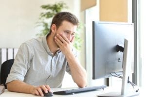 Confused businessman working trying to improve his website with a desktop computer at office